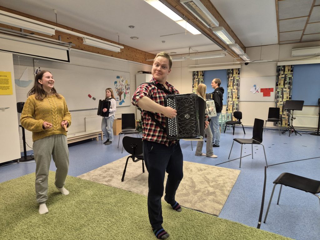 Kuvassa vasemmalla keltaisessa paidassa opettaja Siiri ja harmonikka sylissä opettaja Janne Nivalan toimipisteellä 